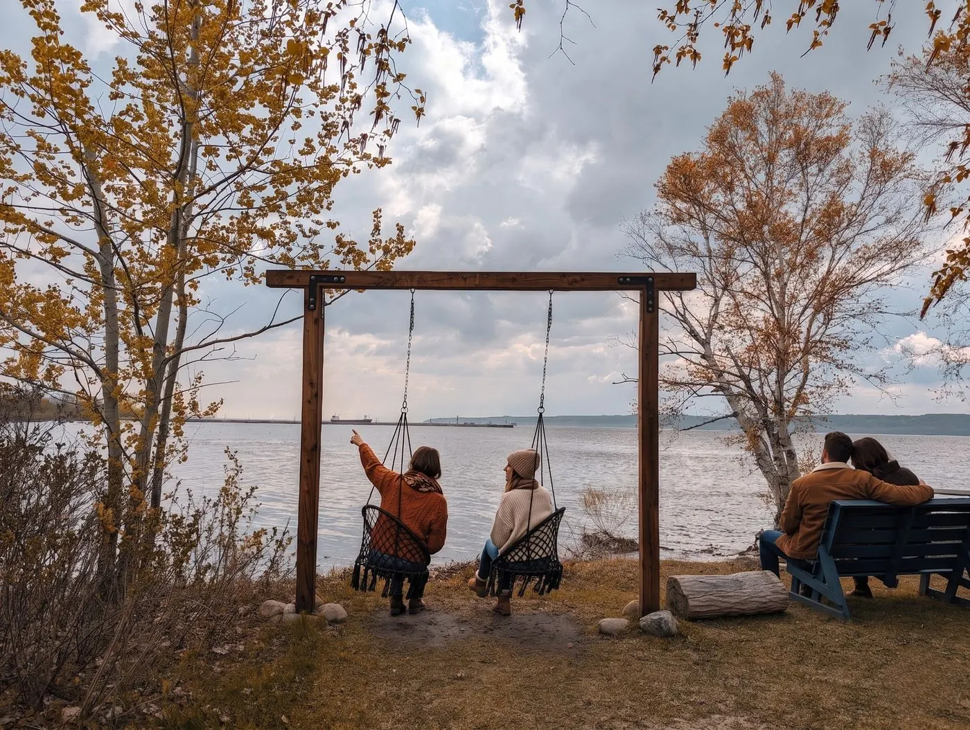Invités sur les balançoires suspendues et un banc sur la berge en automne, face au fleuve Saint-Laurent