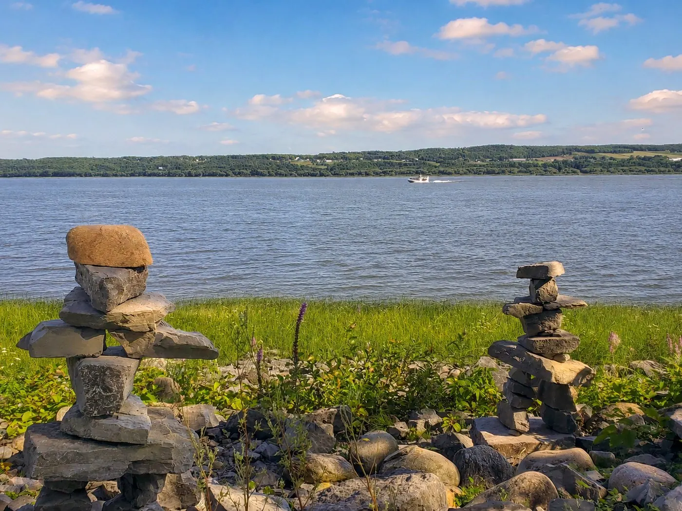 Deux inukshuks sur la berge de Fleuve et Montagnes, face au fleuve Saint-Laurent en été