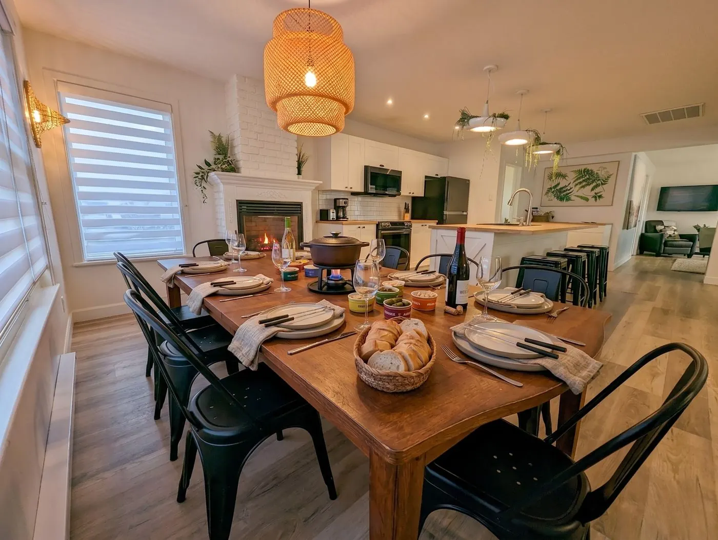 Grande table dressée pour un repas dans un condo, cuisine ouverte en arrière