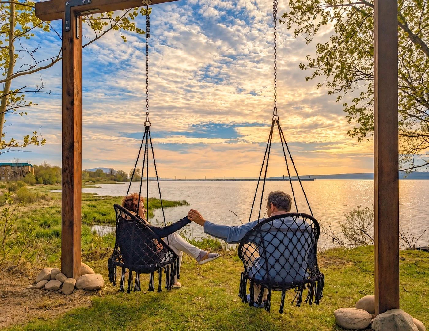 Un couple se tient la main dans les chaises suspendues face au Saint-Laurent, à Fleuve et Montagnes